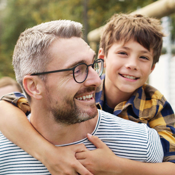 Son riding piggyback on father smiling