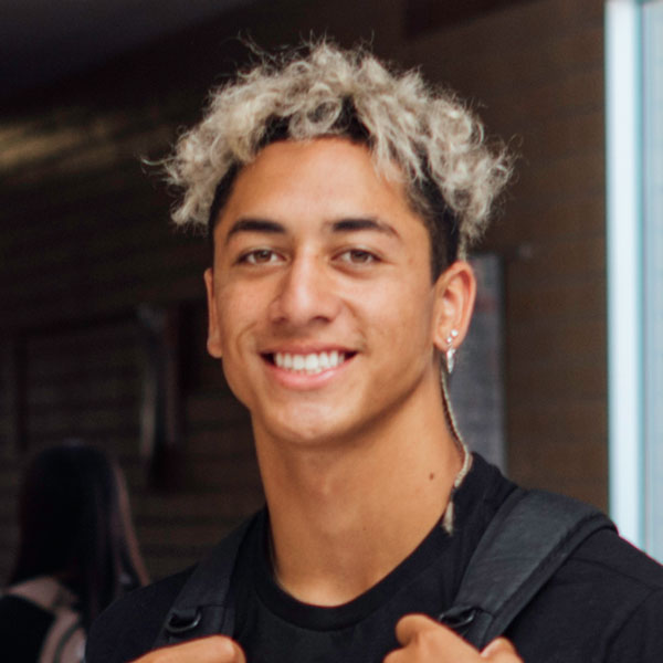 high school boy holding backpack and smiling