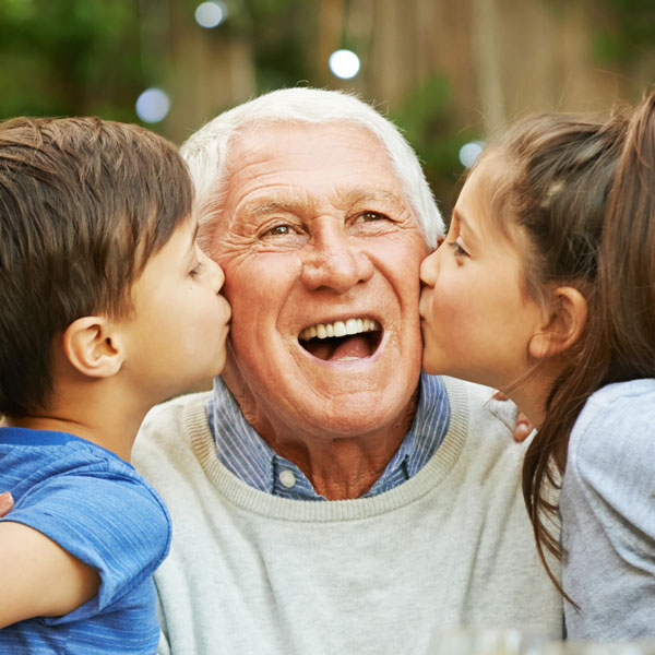 grandkids kissing the cheeks of their grandpa