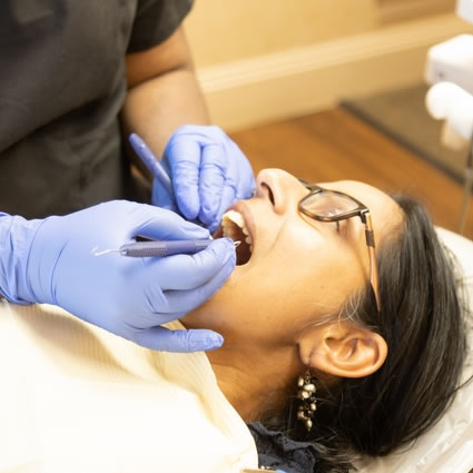 Dental hygenist removing tarter from patient's teeth