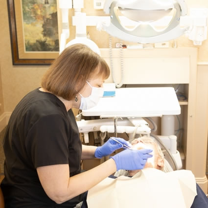 dental hygienist cleaning an older patient's teeth